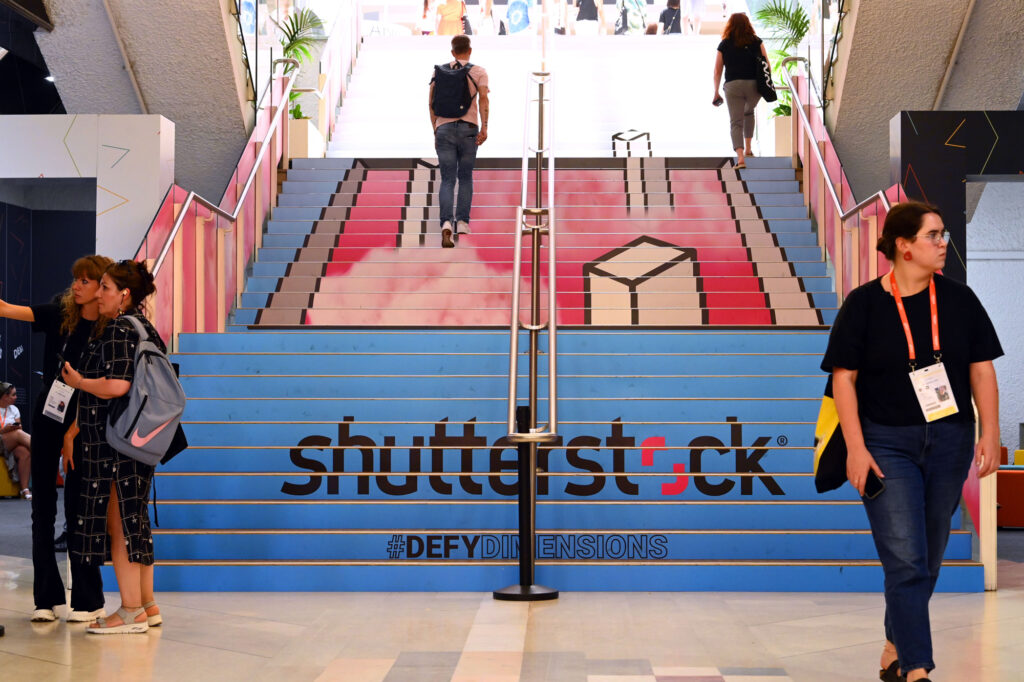 Attendees of the Cannes Lions Festival going up stairs with "Shutterstock #DefyDimensions" printed on the stairs.